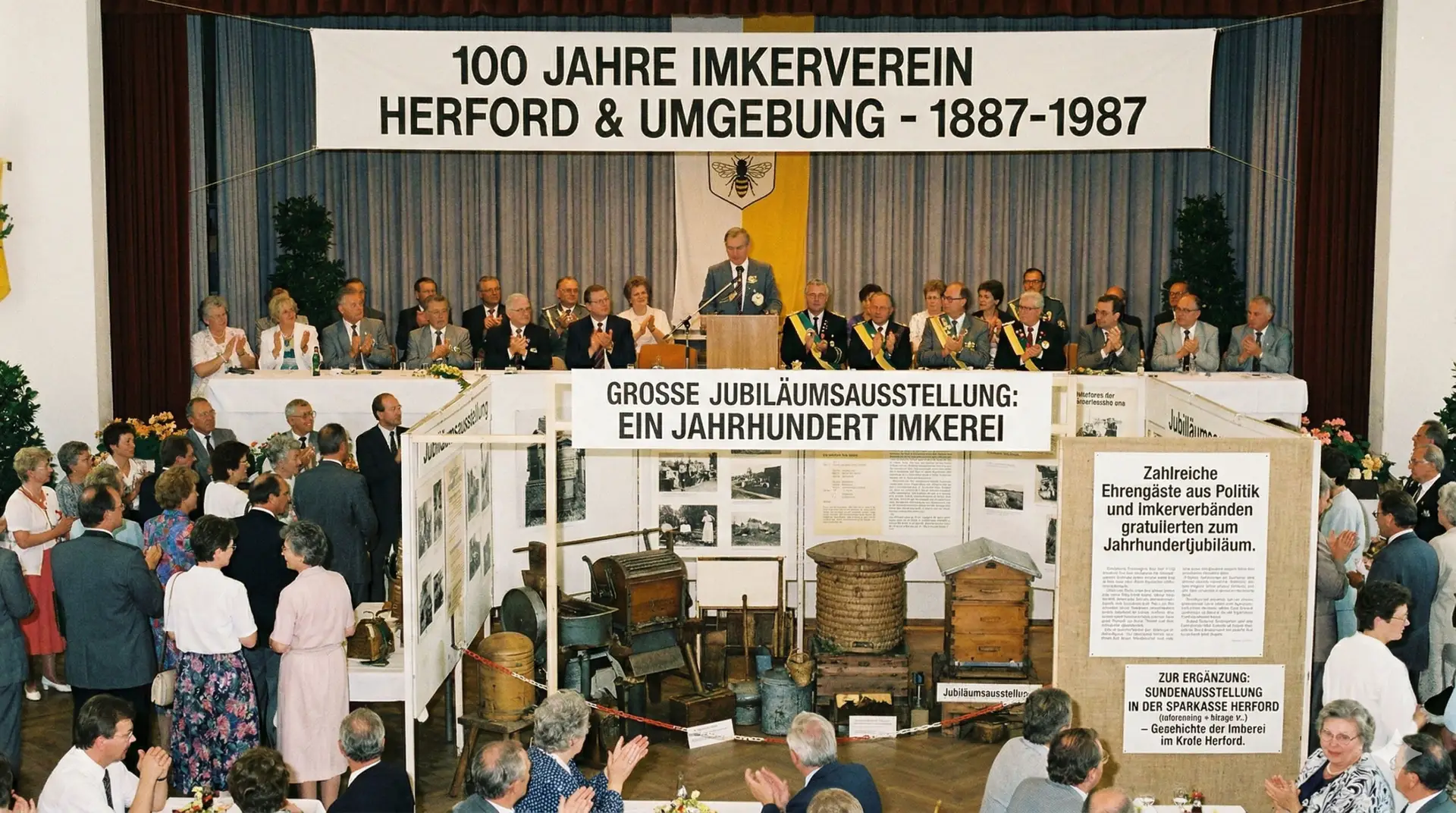 Festakt zum 100-jährigen Jubiläum des Imkervereins Herford & Umgebung im Jahr 1987 mit Rednerpult, Ehrengästen und einer historischen Ausstellung von Bienenstöcken.