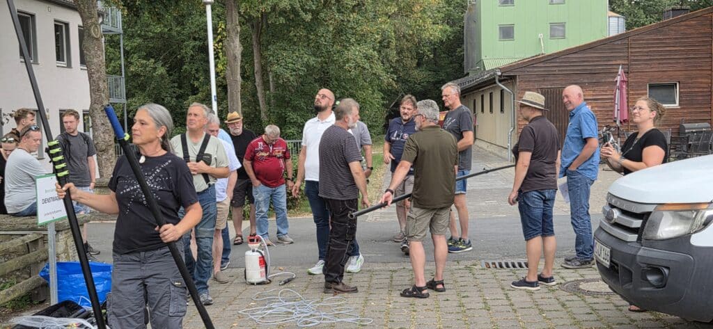 Teilnehmende des Vespa-velutina-Kurses testen und montieren Teleskopstangen und Ausrüstung zur Nestentfernung im Außenbereich von Haus Düsse.